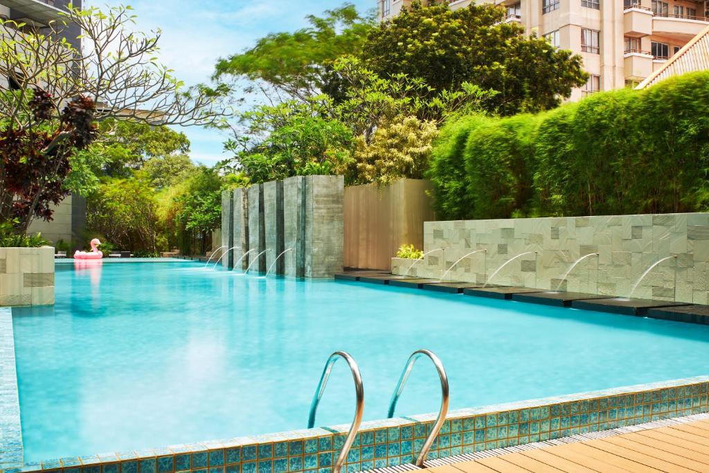 雅加达eL Hotel Jakarta的一个带椅子和树木的大型游泳池