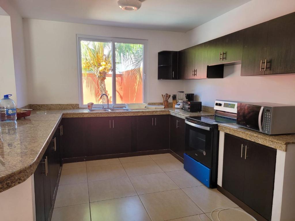 IztapaCasa en condominio monterrico的厨房配有黑色橱柜、水槽和窗户。