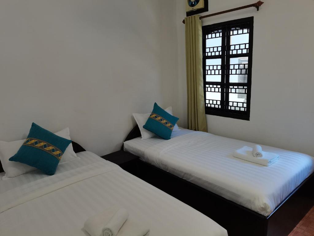 琅勃拉邦PHAI GUESTHOUSE的两张睡床彼此相邻,位于一个房间里