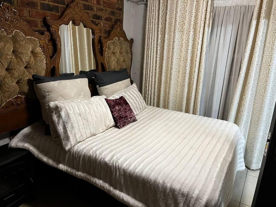 比勒陀利亚Berry’s cosy cottage的卧室内的一张带白色床单和枕头的床