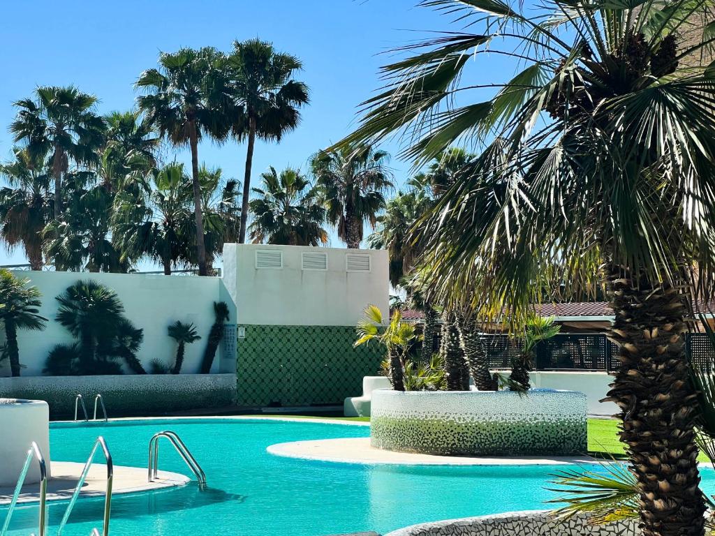 奥罗佩萨德尔马Tropical y Lujoso Complejo的度假村内棕榈树游泳池