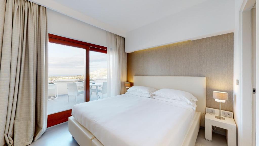 奥斯图尼蒙特萨拉戈酒店的一间带白色床的卧室和一个阳台