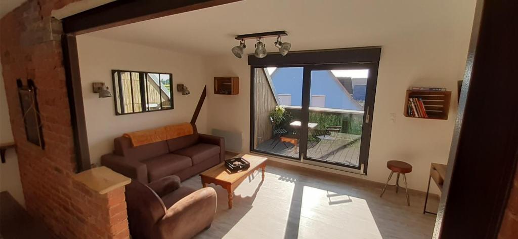 豪森Le grenier de Véro的带沙发和大窗户的客厅