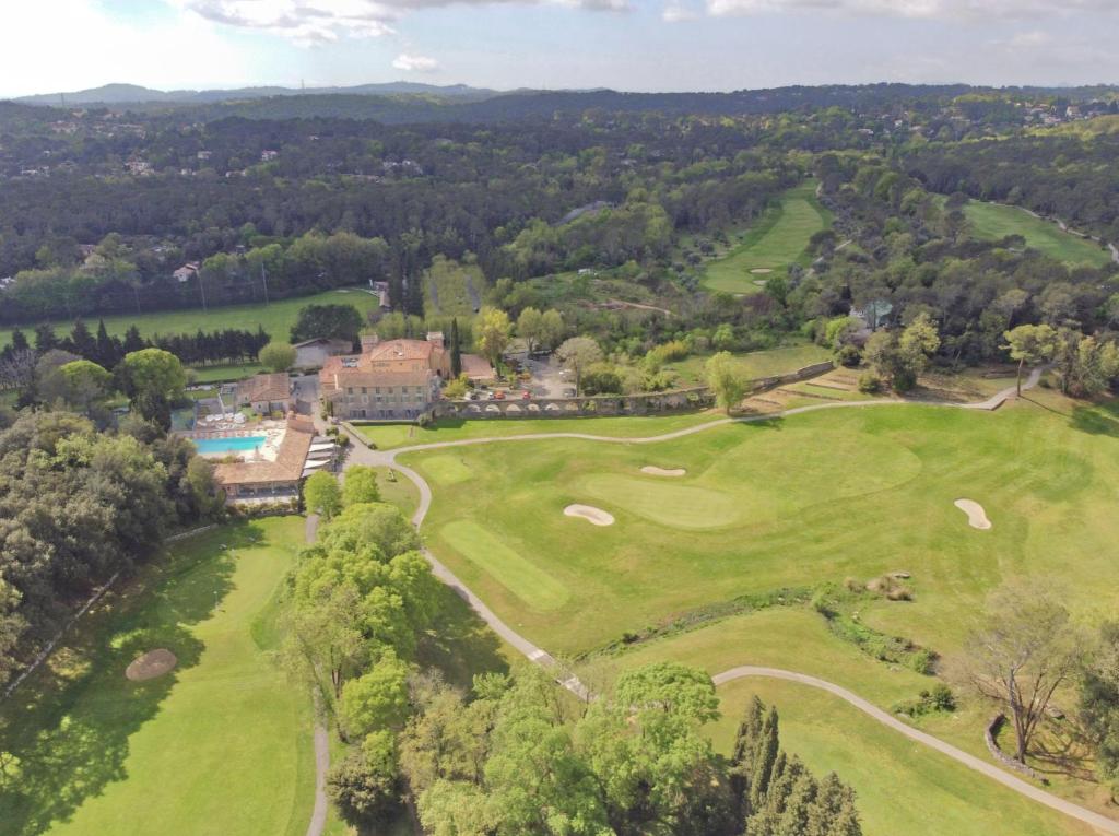 瓦尔邦讷Hôtel Golf & Spa Château de la Bégude The Originals Collection的享有度假村高尔夫球场的空中景致
