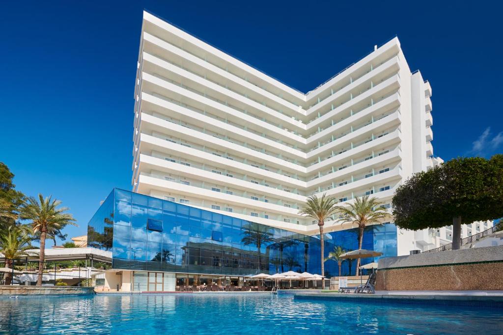 帕尔马海滩陶鲁斯公园集团酒店的一座白色的大建筑,前面设有一个游泳池