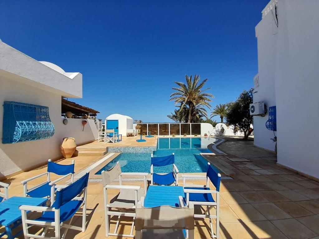 Al ḨaddādahDar Lagune Djerba的一个带蓝白色椅子的游泳池和一个游泳池