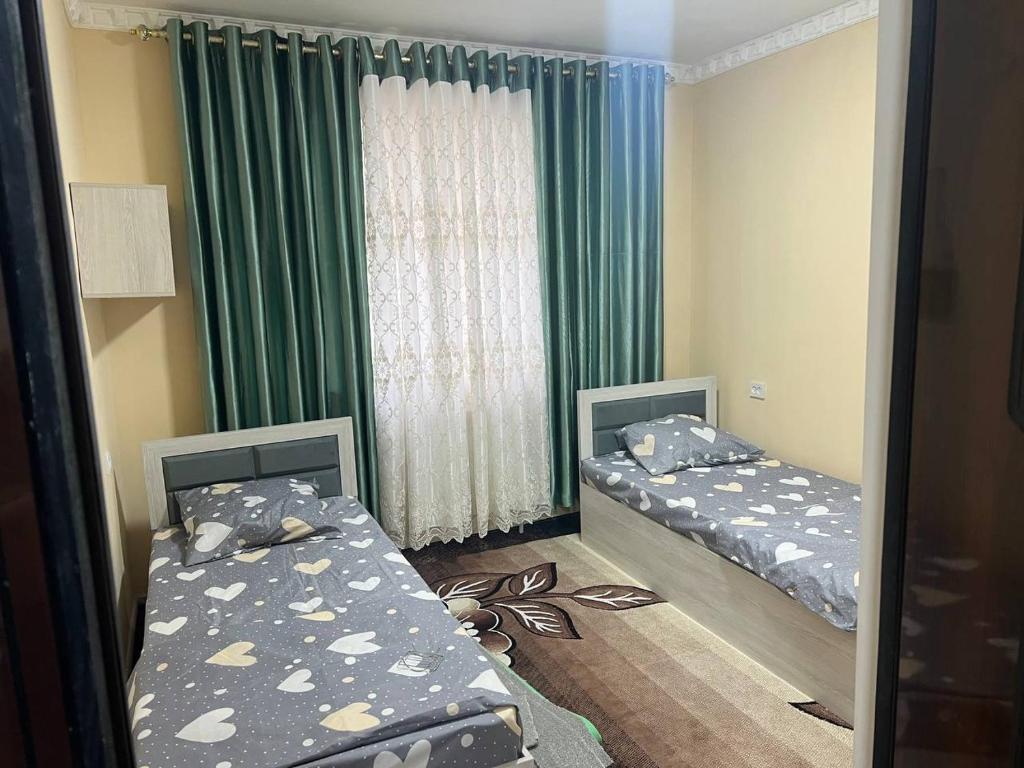 希瓦Ancient Khiva Apartment的一间卧室设有两张床,窗户设有绿色窗帘