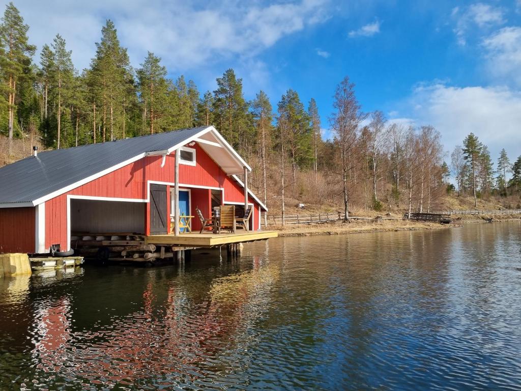 MjällomBoathouse的水面上码头上的红色房子