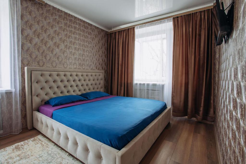 库斯塔奈1-комнатная квартира в центре на Аль-Фараби 93的一间卧室配有一张带蓝色床单的床和一扇窗户。