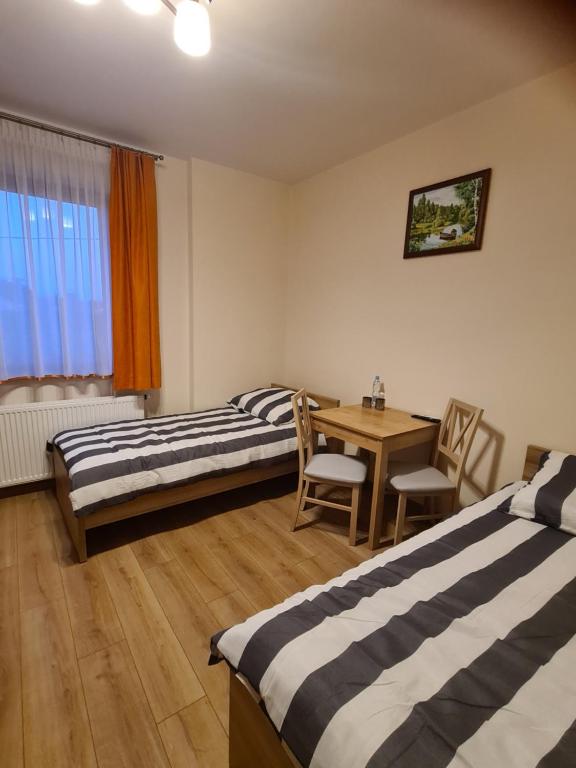 GolczowiceMARMI Noclegi的客房设有两张床、一张桌子和一张桌子以及椅子。