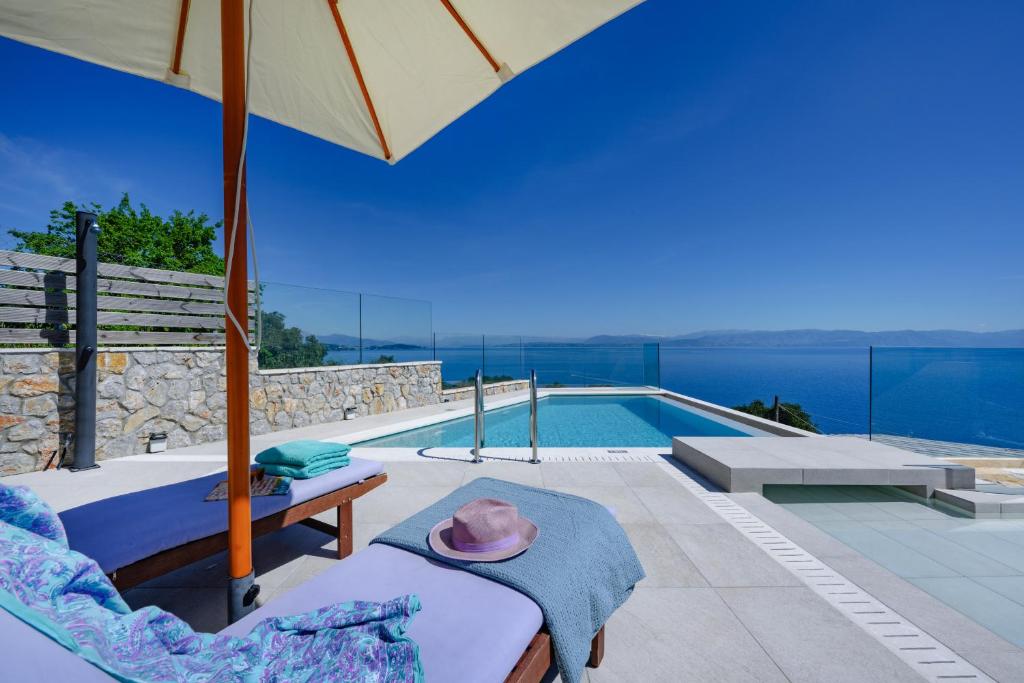 贝尼蔡斯Sea & Cliff Luxury Suites的一座带游泳池和遮阳伞的别墅