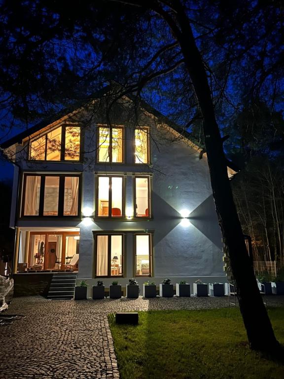 皮什Leśna Residence & SPA的夜晚有灯的大白色房子