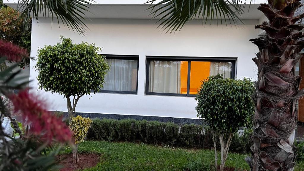 拉巴特Cozy Appartement in a Villa close to Mahaj Riad Rabat的一间白色的房子,前面有窗户和灌木丛