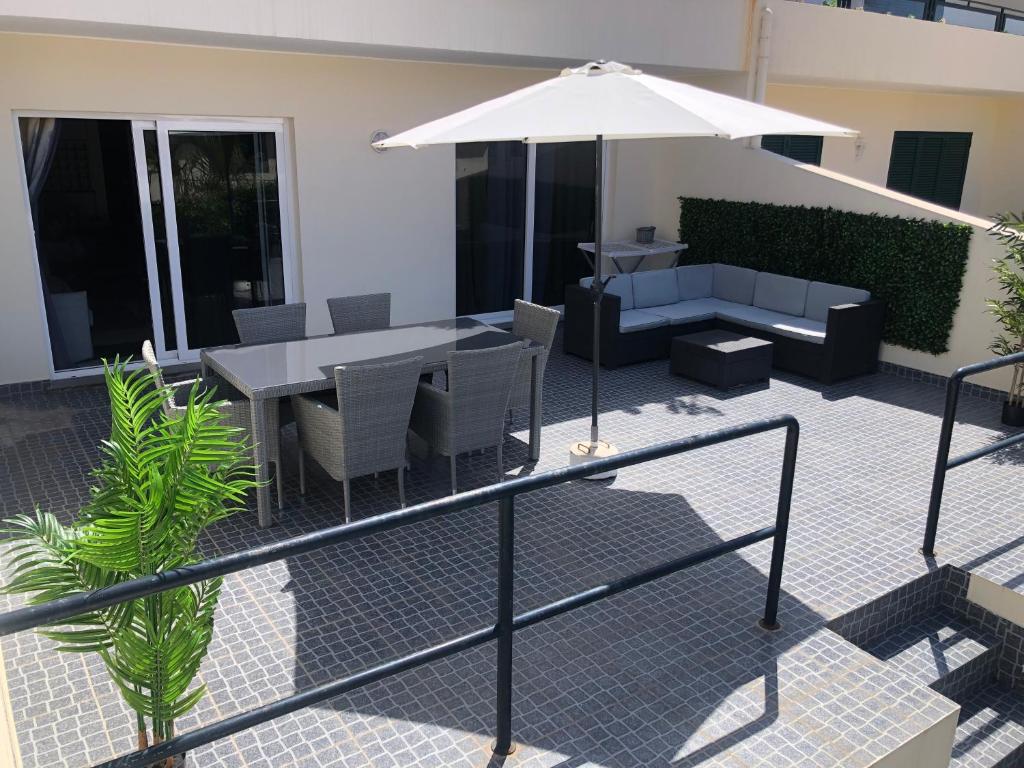 丰沙尔Ocean Dream Apartment的庭院配有桌椅和遮阳伞。