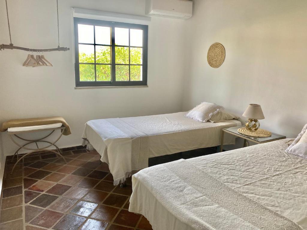 法鲁Casa Pedra Rosa - VINHAS de NEXE的客房设有两张床和窗户。