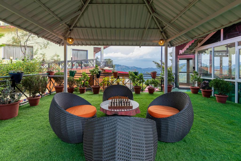 西姆拉Maple Resort Chail的天井配有2把藤椅和1张桌子,位于草地上