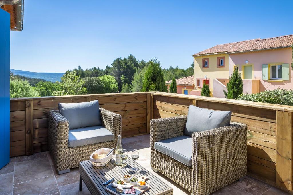 鲁西永Domitia Roussillon Appartement Luberon的庭院配有2把藤椅和桌子