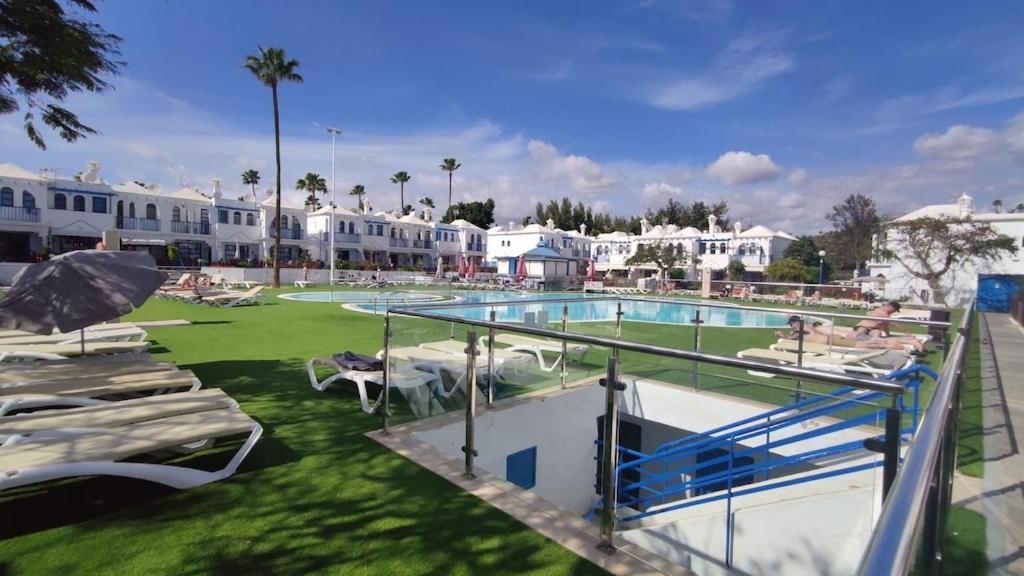 马斯帕洛马斯Bungalow in the sun of Maspalomas with large pool的一个带躺椅的游泳池和一个度假村