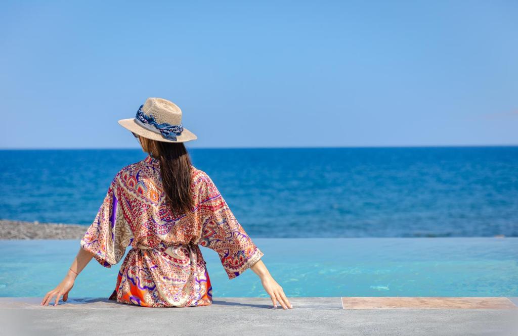 易莫洛林Casa di Mare Luxury Villas的站在海滩上看着大海的女人