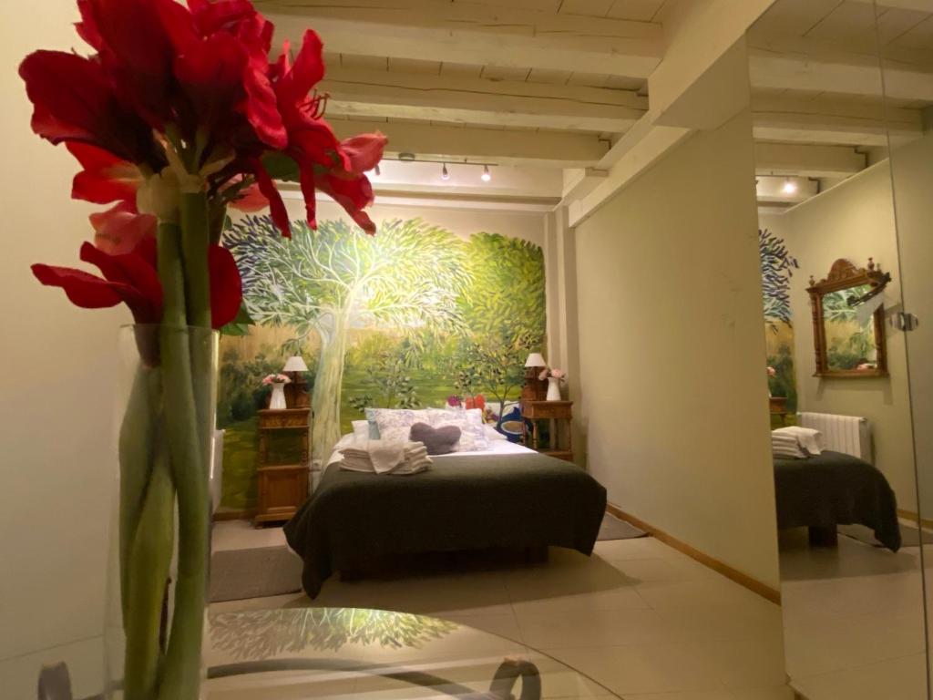 塞哥维亚利菲托勒丽尔公寓酒店的一间设有床铺和鲜花花瓶的房间
