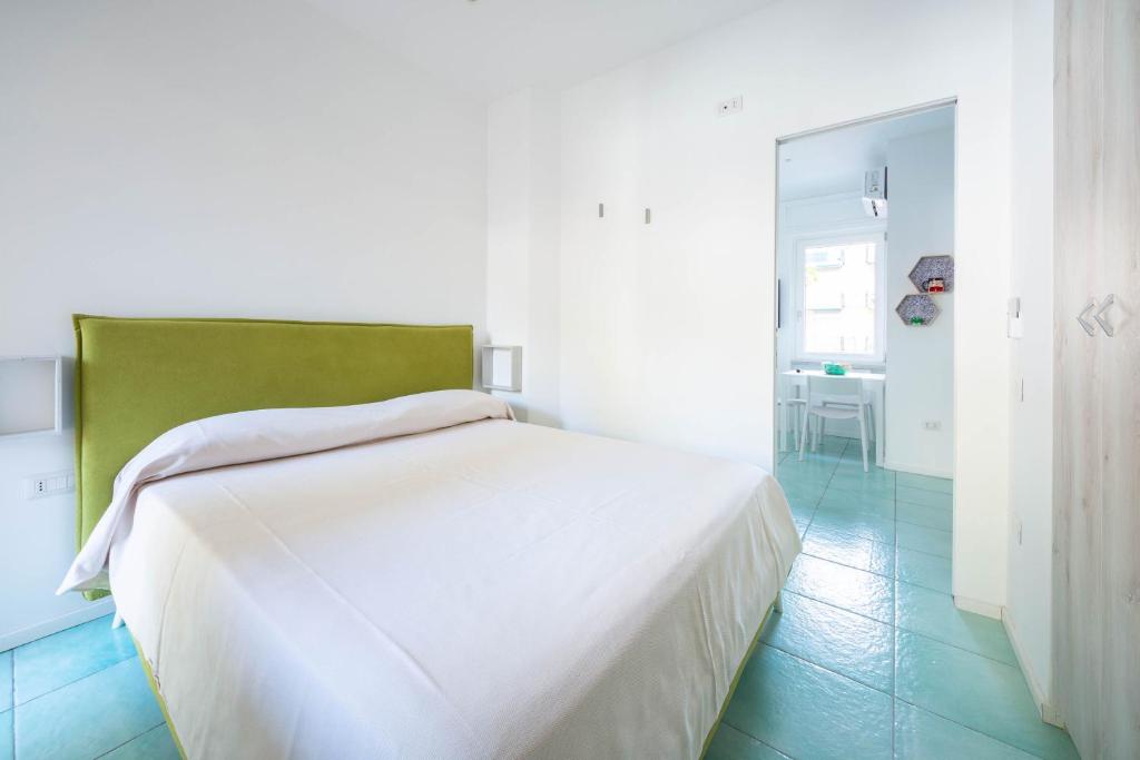 马奥莱Dependance Panorama的白色的房间里一张白色的床,上面有绿色的床头板