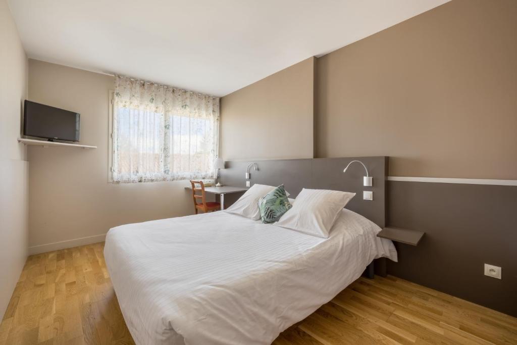 索恩河畔自由城Hôtel Newport的卧室配有一张白色的大床和一张桌子