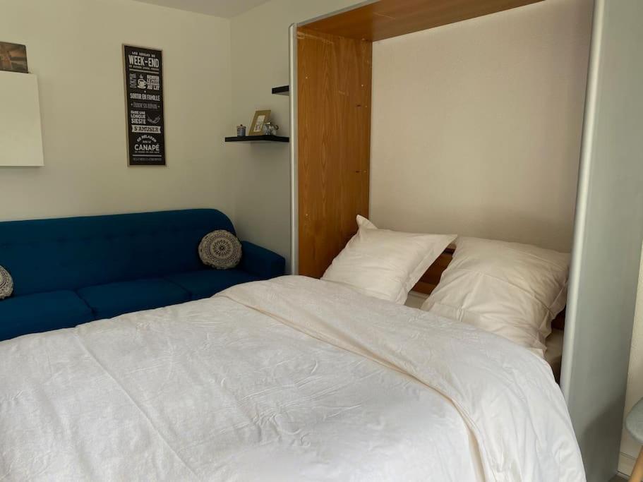 梅尔·莱斯·拜恩斯Trimaran Studio 10 mètres de la plage avec balcon/terrasse的一间卧室配有一张床和一张蓝色的沙发