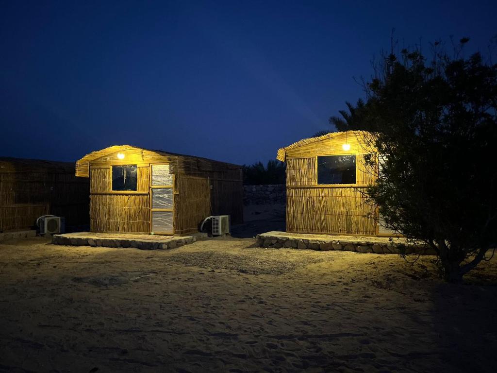 努韦巴Mazih beach camp的两个小木结构,晚上有灯