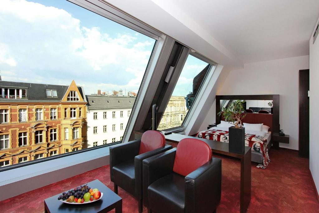 柏林ARCOTEL Velvet Berlin的客房设有带床和椅子的大窗户。