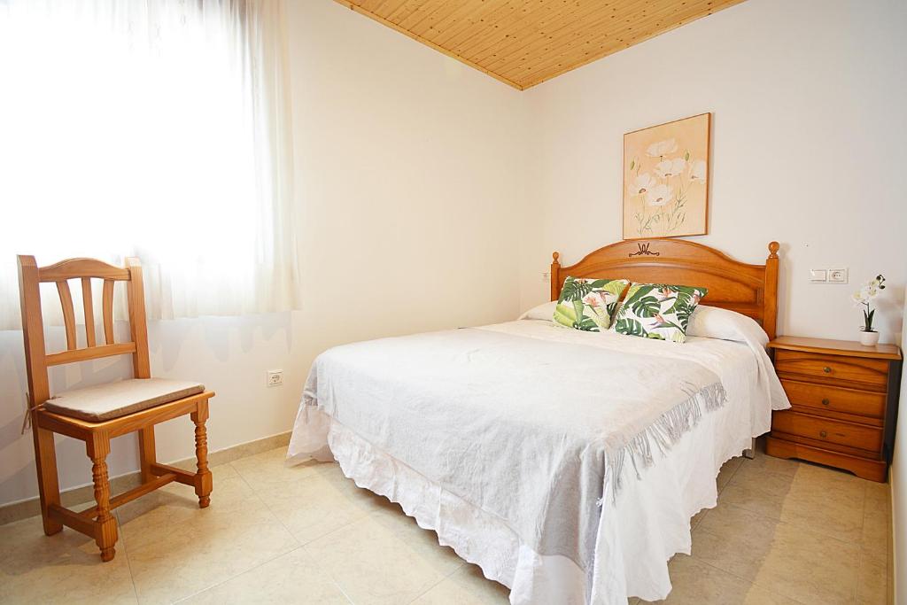 格罗韦Casita adosada de playa en Porto Meloxo - Grove的卧室配有床、椅子和窗户。