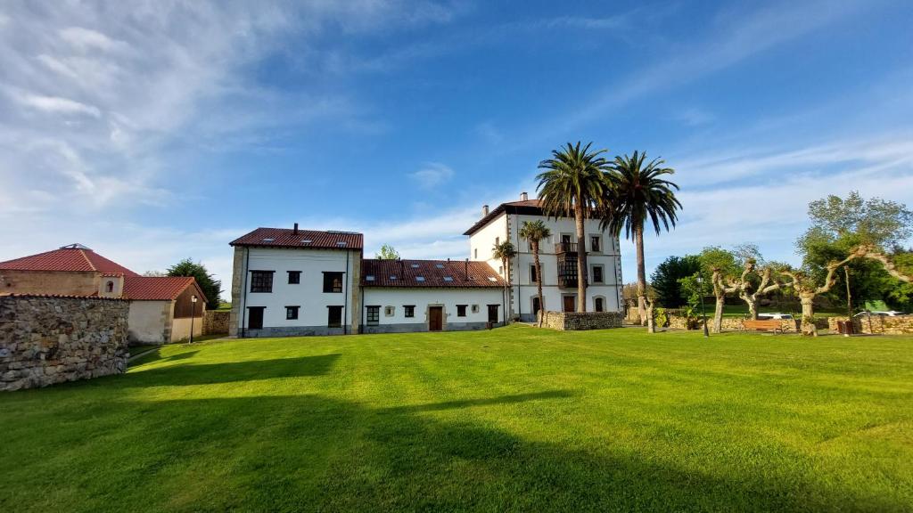 NoriegaPreciosa Casa de Indiano En Noriega (Asturias)的一片大草场,有建筑和棕榈树