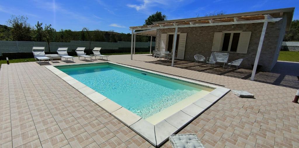 Giano VetustoJanus Casa nel Verde - Relax Pool & Spa的一个带椅子的游泳池以及一座房子