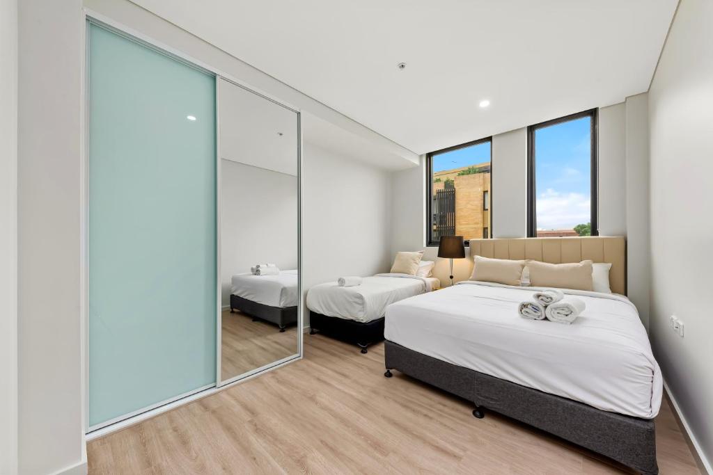 悉尼Elegant and Modern Style Apartments in Dulwich hill的一间卧室设有两张床和大窗户