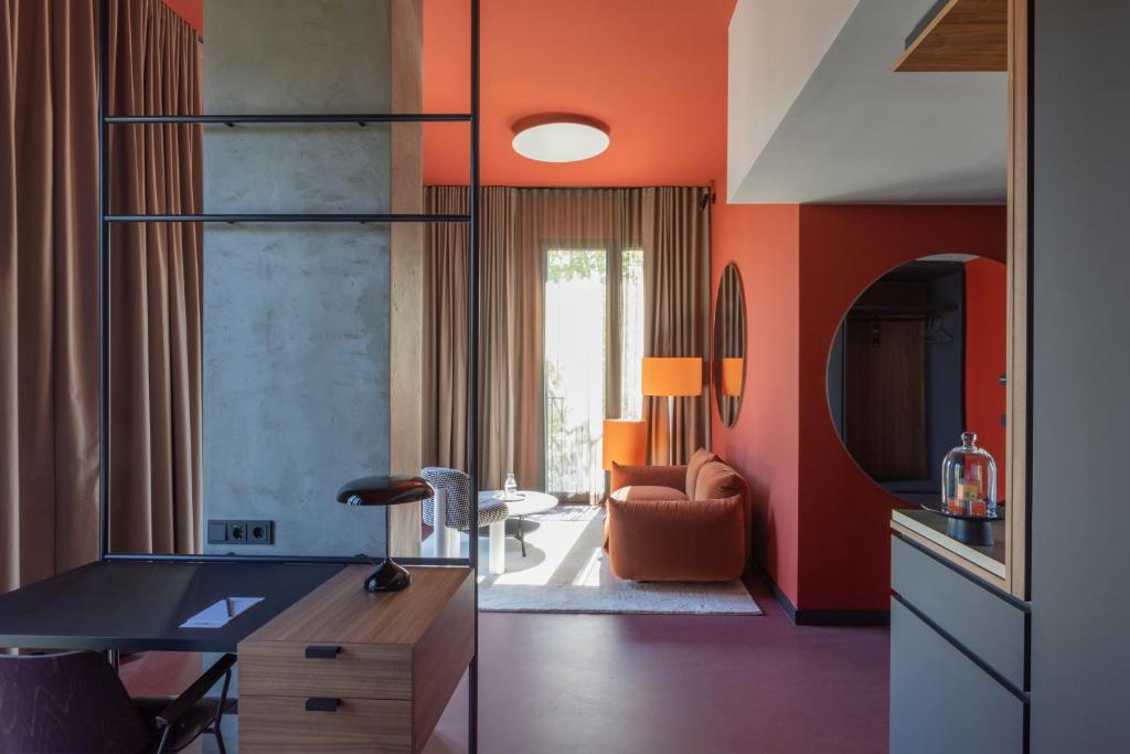斯图加特EmiLu Design Hotel的客厅设有橙色墙壁和书桌