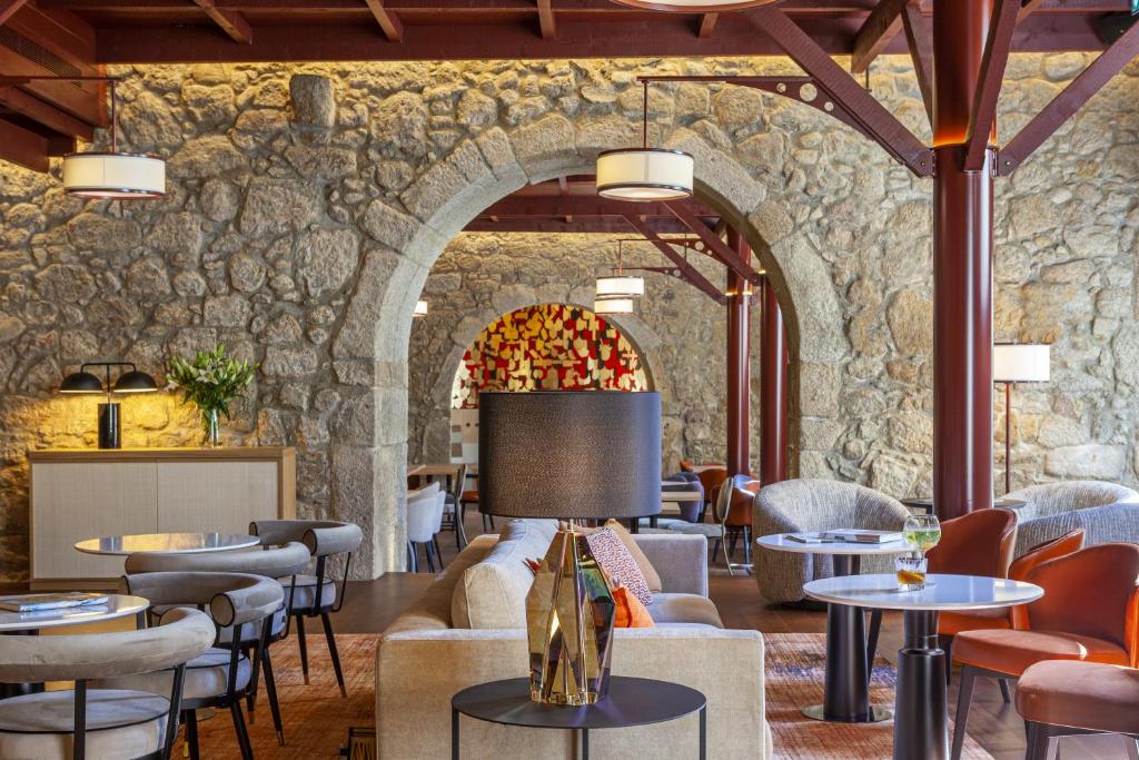 波尔图Hotel das Virtudes的餐厅设有石墙和桌椅