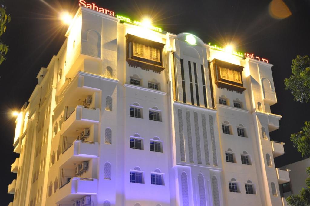 马斯喀特撒哈拉公寓酒店的白色的建筑,晚上有灯