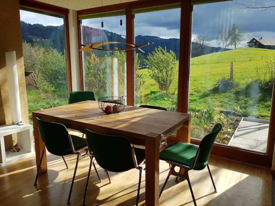 阿尔贝施文德Urlaub in Alberschwende的一张带绿椅的餐桌和大窗户