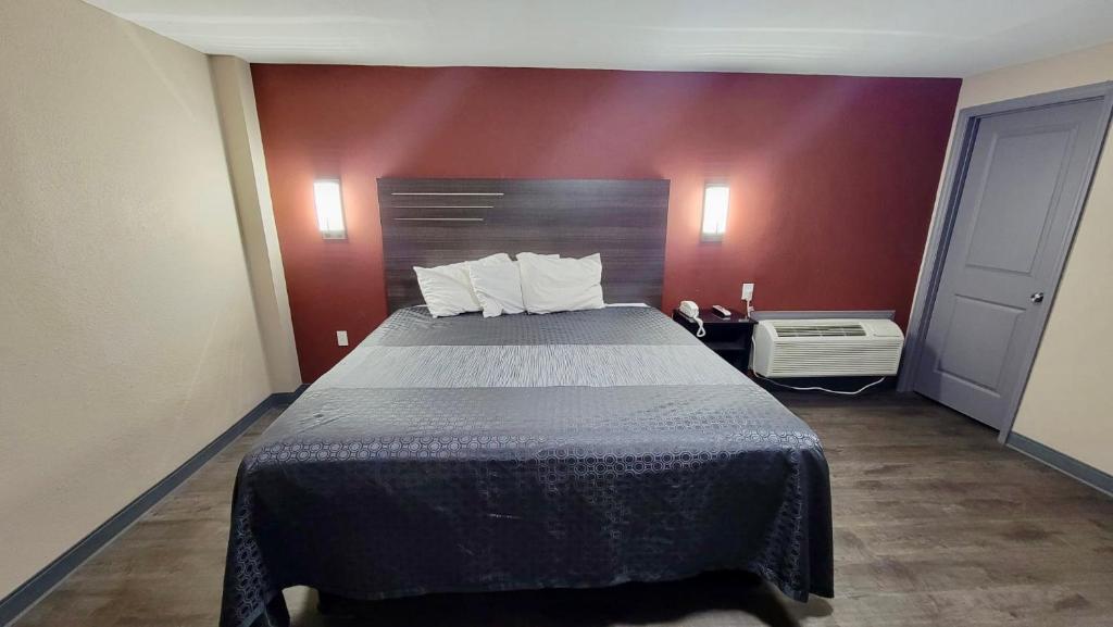 弗洛伦斯Budget Inn的一张大床,位于一个红色墙壁的房间