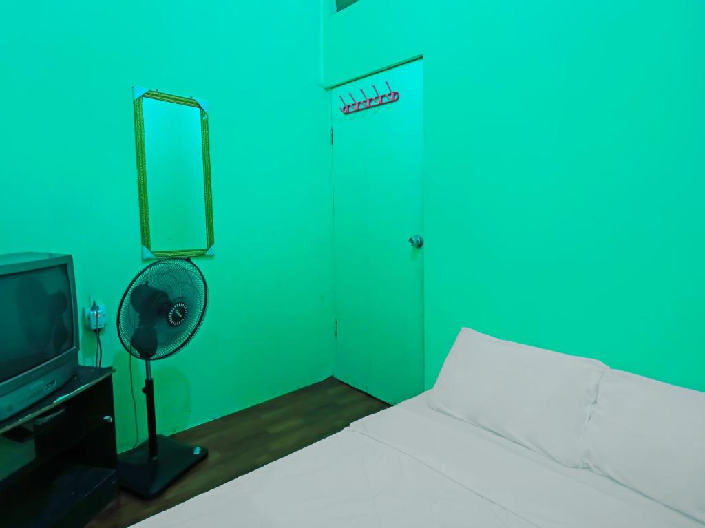 名古屋SPOT ON 92538 Joyoakis Homestay Syariah的一间卧室配有一张床、一台电视和一扇绿门