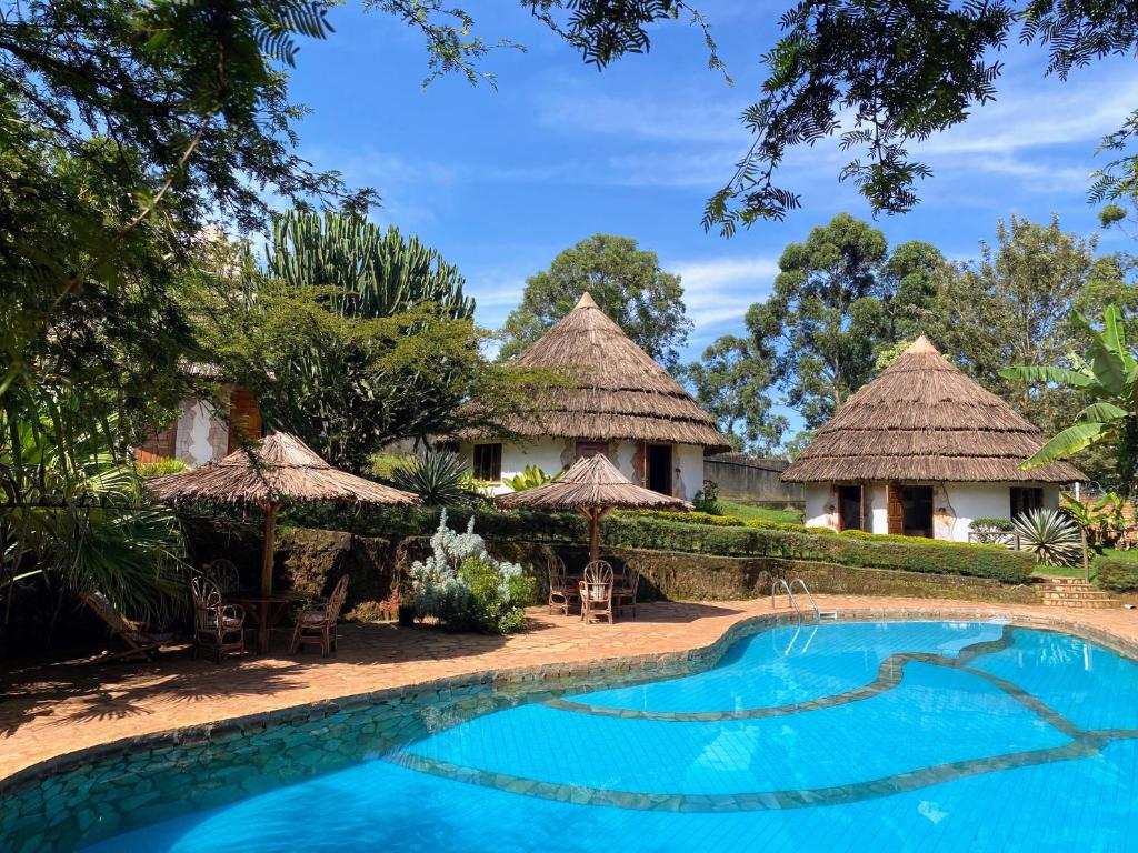 MasakaBanda Lodge的一个带游泳池和茅草小屋的度假酒店
