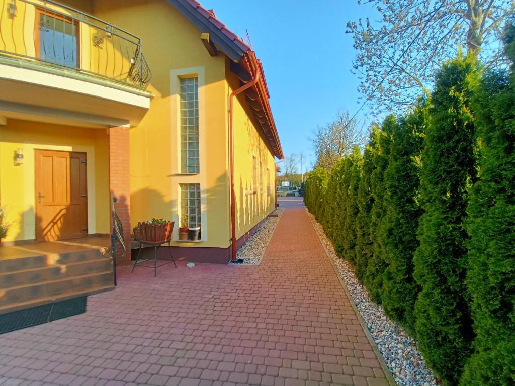 绿山城Noclegi Zielona Góra u Moni的一条黄房子,在树 ⁇ 旁边设有砖边人行道
