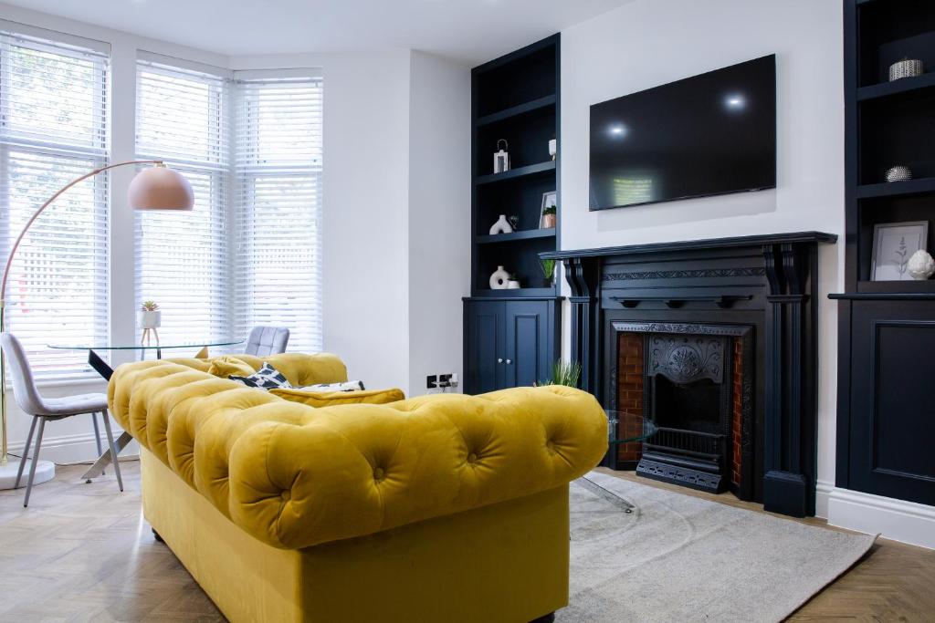 卡迪夫Designer Cardiff Apartments的带壁炉的客厅内的黄色沙发