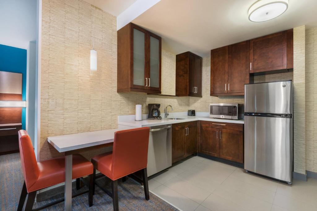 夏洛特Residence Inn by Marriott Charlotte City Center的厨房配有桌子和不锈钢冰箱。