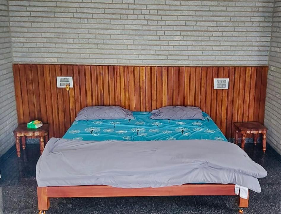 ChannarāyapatnaKashi Farm House的一张带木制床头板和两张桌子的床