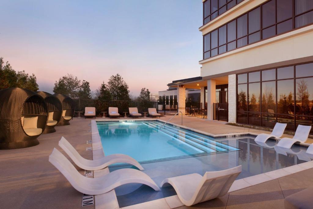 绍斯莱克Delta Hotels by Marriott Dallas Southlake的一座带白色椅子的游泳池和一座建筑