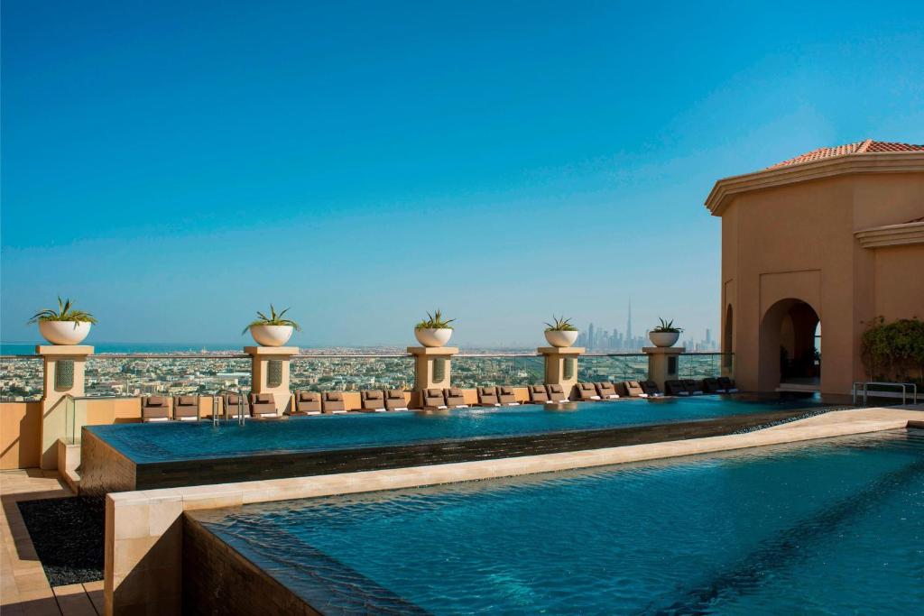 迪拜迪拜阿联酋购物中心喜来登酒店的一个带椅子的游泳池,背景是大海