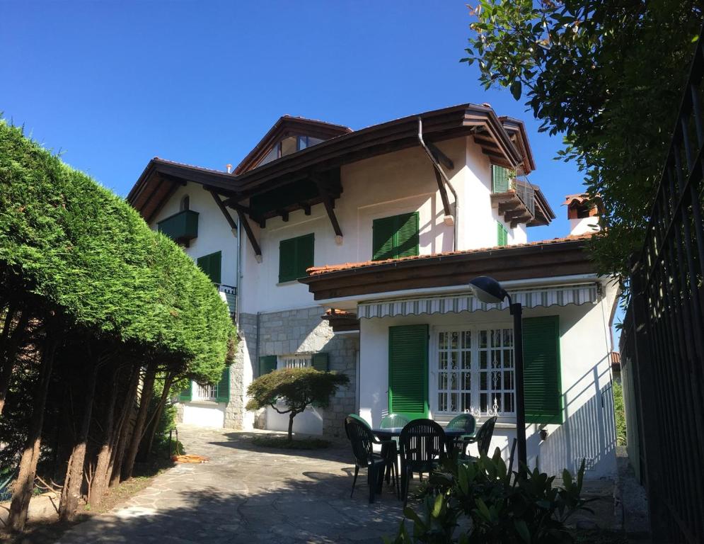 卡尼洛瑞维拉Appartamento Tennis的庭院内带绿色百叶窗和椅子的房子