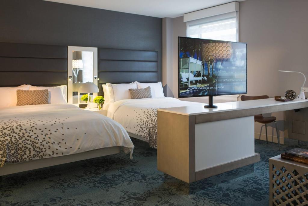奥尔巴尼奥尔巴尼万丽酒店 的一间卧室配有两张床和一张书桌及电视