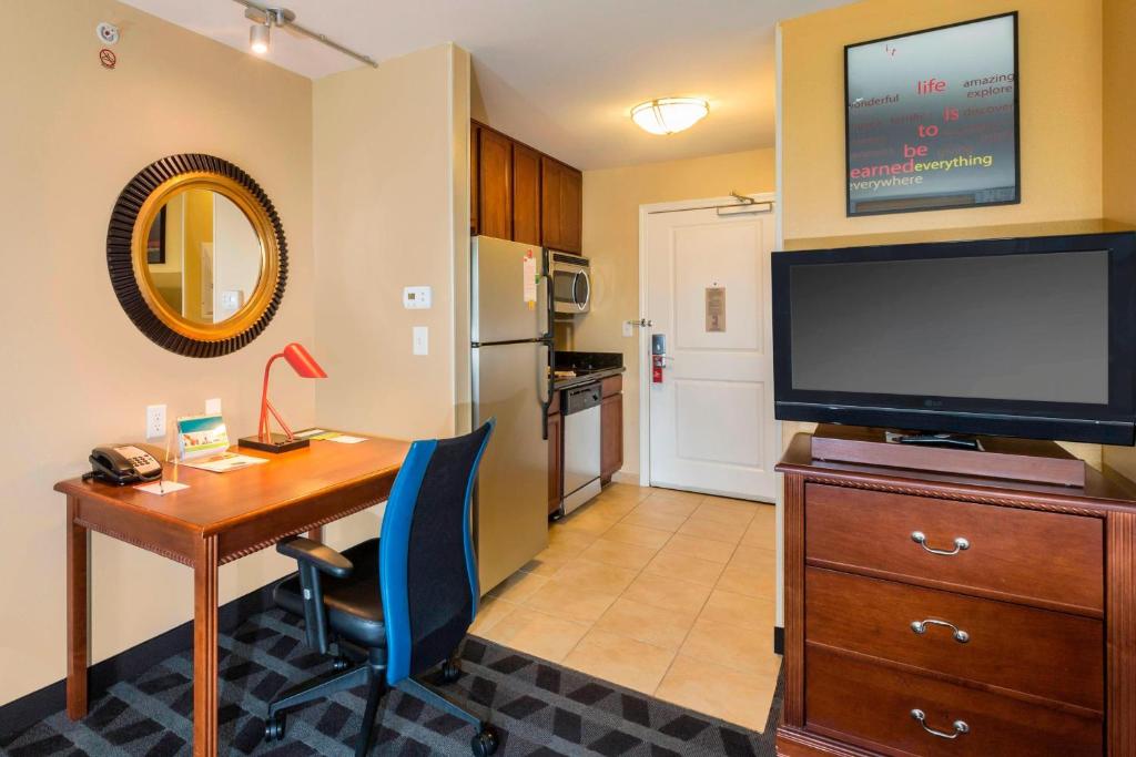 兀兰北休斯顿唐普雷斯套房/谢南多厄酒店的客厅配有书桌、电视和书桌、四柱四柱床
