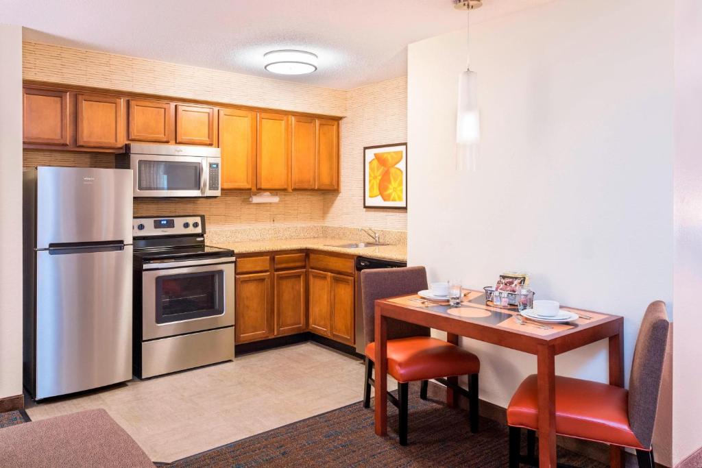 亨茨维尔亨茨维尔公寓式酒店的厨房配有木制橱柜和桌椅
